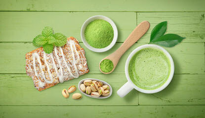 Matcha latte tea display with pistachio nuts and pastry on bright green wood background