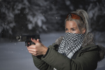 Fototapeta na wymiar Girl shooter with a pistol in cold winter. Side view.