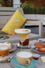 Lady Cocktail or mocktails in elegant glass surrounded by bakery and coffee on gray table. Summer drink in crystal glass.
