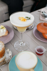 Lady Cocktail or mocktails in elegant glass surrounded by bakery and coffee on gray table. Summer drink in crystal glass.