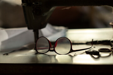 Sewing machine and glasses on the table. Selective focus.