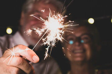 cute couple of two senior in love together the new year night playing with the sparklers in their...