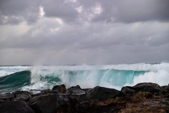 Ocean waves crash on the shore of the tropical island beach Kauai in Hawaii. 