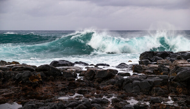 Ocean waves crash on the shore of the tropical island beach Kauai in Hawaii. 