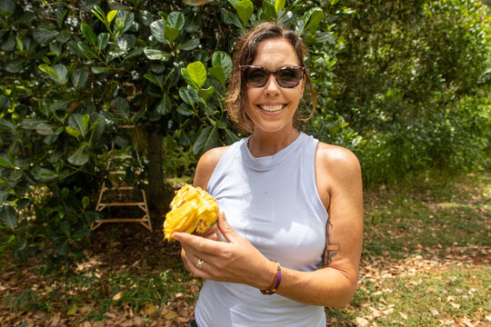 Smiling woman holding fresh cut jackfruit in a tropical island jungle in Kauai, Hawaii. 