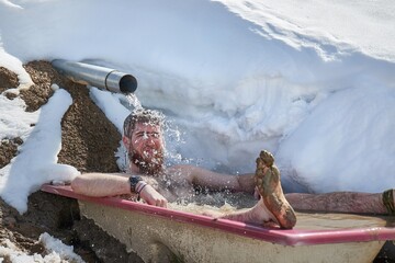 Man taking cold bath in a snowy bathtub