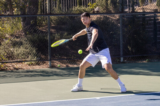 Male Tennis Player in Action on Outdoor Court During Sunny Match