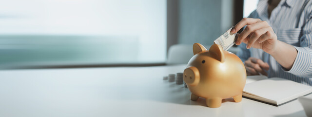 Accountant is putting money into a piggy bank, Financier is bringing savings methods to clients who come to receive advice, Employees are taking customers' savings and keeping them safe. - obrazy, fototapety, plakaty
