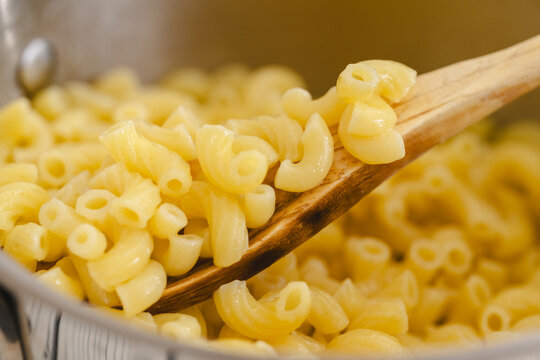 Cooked pasta in a pot. Spoon of elbows pasta close-up