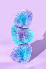 Fototapeta premium Three Stacked Heart-Shaped Quartz Gemstones in Blue and Purple on Lavender Background