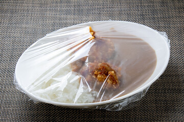 ラップをかけられた料理。(鶏唐揚げトッピングカレーライス)。
