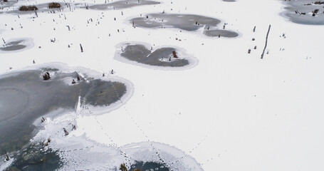 Aerial snowy view. Winter season. White earth cover with frozen lakes cold cloudy weather countryside wildlife landscape drone.