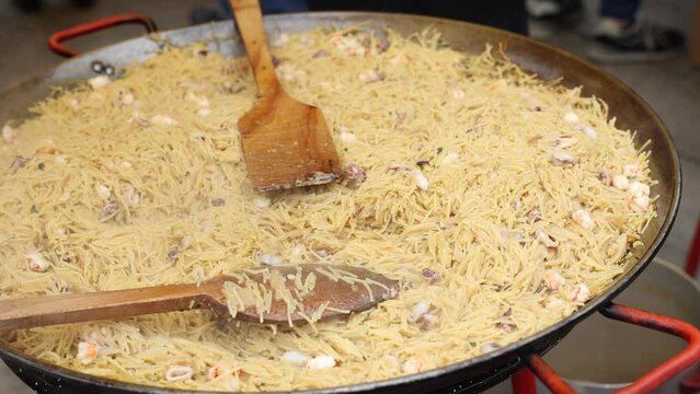 Cooking a traditional dish Valencian cuisine Fideua de Marisco during a street holiday in Spain. Close-up image