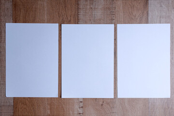 Three empty white vertical rectangle poster mockups on wooden background