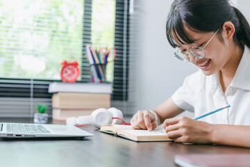 Educate at home. Asian school girl studying with books laptop preparing for test exam writing essay doing homework at home, Back to school. © AungMyo