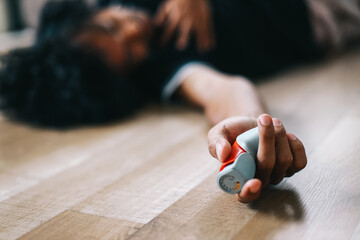 Man lying on the floor having asthma attack while holding asthma inhaler - obrazy, fototapety, plakaty