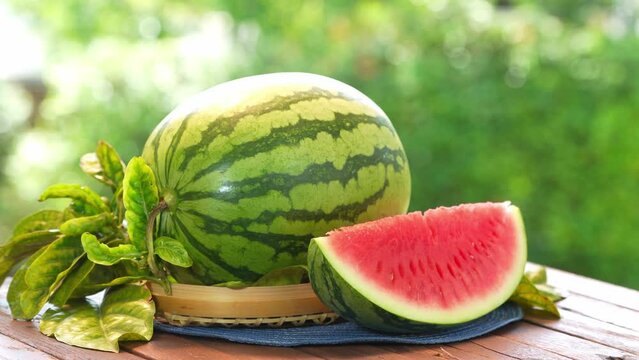 Watermelon  on wooden table, Fresh Giant Seedless Watermelon with slices on blurred greenery background.