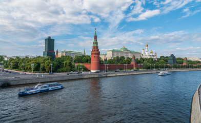 Obraz premium View of Kremlin with Vodovzvodnaya tower, Grand Kremlin Palace from repaired Bolshoy Kamenny Bridge in Moscow city on sunny summer day. Cruise ship sails on the Moscow river