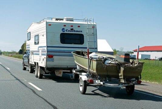 Coachman traveling camper towing fishing boat with a Johnson 20 outboard motor on the highway. An envious lifestyle. Nisswa Minnesota MN USA