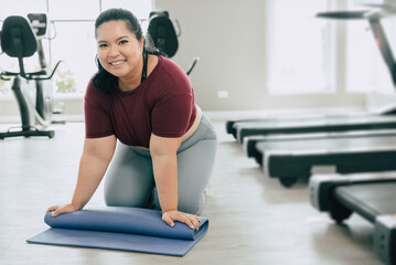 fat woman in fitness sport club studio with yoga mat. portrait plus size  female roll pilates mat happy smiling after training class.