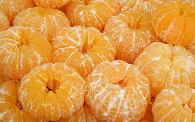 Many peeled fresh ripe tangerines as background