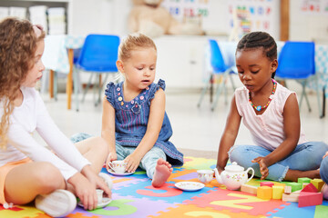 Kids, tea party and playing for fun in school with friends, together and bonding. Diversity, little girls and face with toy on mat for child development, motor skills and growth for future in daycare - obrazy, fototapety, plakaty