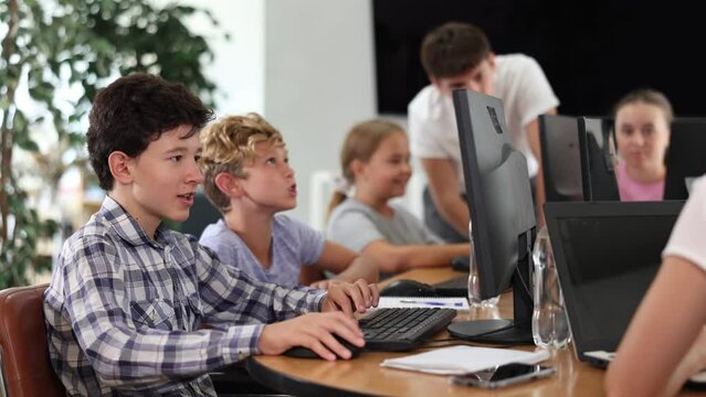 Side view of rows of students in a computer class - boys solving computer problems. High quality 4k footage