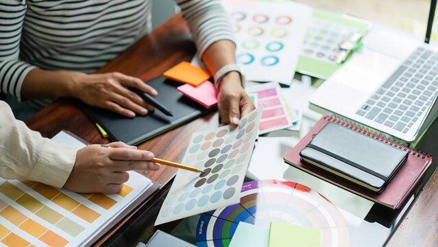 Two creative graphic designers discuss about colors swatch to designing project and draw on tablet