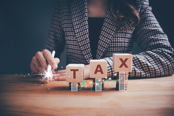 Businesswoman pointing wooden cube block with TAX text and coins stacking. Tax deduction planning,...