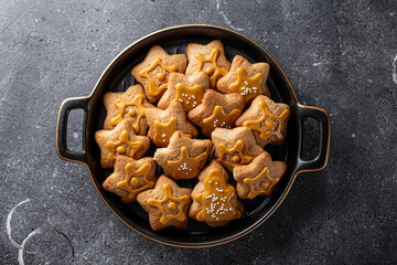  Festive Christmas cookies decorated with golden icing in a black plate. Dark grey background, top view
