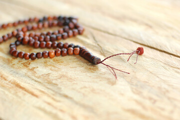 Muslim prayer rosary beads isolated on wooden background.