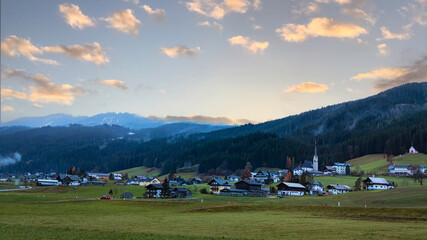 The Misty scene with Alpine green fields and traditional wooden houses view of the Gosau village at autumn mood