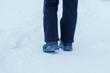 Fototapeta na wymiar traveler walking on the snow, closeup waterproof boots or shoes during hiking on snowy forest. Winter season