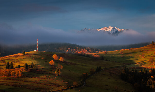 Osturna, Slovakia - Panoramic view on High Tatras mountains National Park on a sunny autumn morning with warm golden sunrise colors on foliage, radio tower and foggy mountains at background