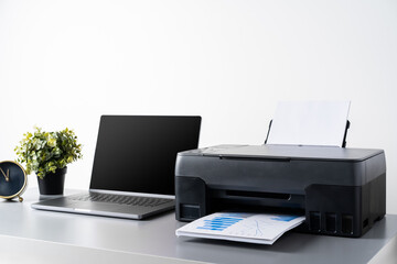Printer and laptop on grey table in office