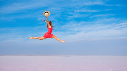 Young woman jumping in the air on Dead sea, salt shore, salt lake on blue sky