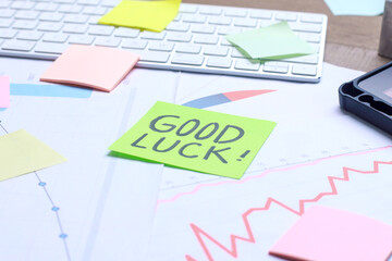 Sticky note with Good Luck handwriting on papers with charts diagrams and keyboard. Office work...