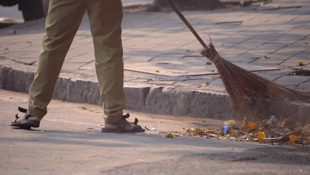 Street cleaning male municipal worker in uniform sweeping the sidewalk with a broom in old mumbaiStreet cleaning male municipal worker in uniform sweeping the sidewalk with a broom in old mumbai