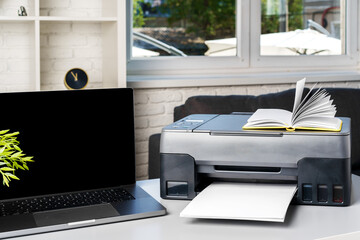 New modern printer and laptop in the office on table