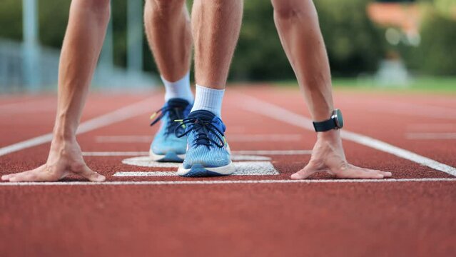 Close-up pan shot of runner at the starting position of running track