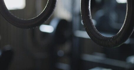 Static view of rings in motion, gymnasium in the background. Close-up