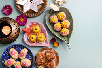 Obraz na płótnie Canvas Indian assorted Diwali sweets or mithai with diya and flowers. Festive gift idea. Kaju katli, dry fruits peda, barfi, cashew nut barfi, marzipan, khoya cakes. christmas sweets. copy space.
