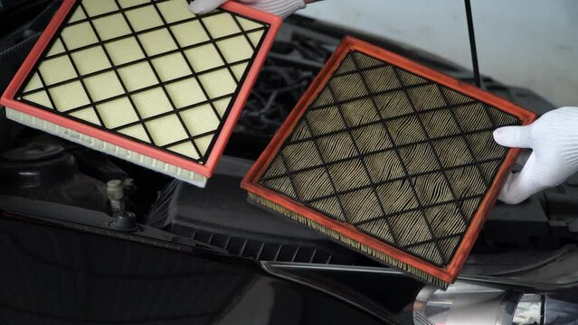 mechanic holds a new car air filter to replace the old car filter,Replacing a new air filter in a passenger car