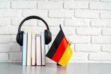 Stack of books and flag of Germany on desk. German language learning concept