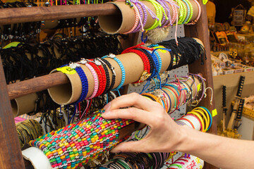 Hand of woman with colorful bracelets on stall at bazaar