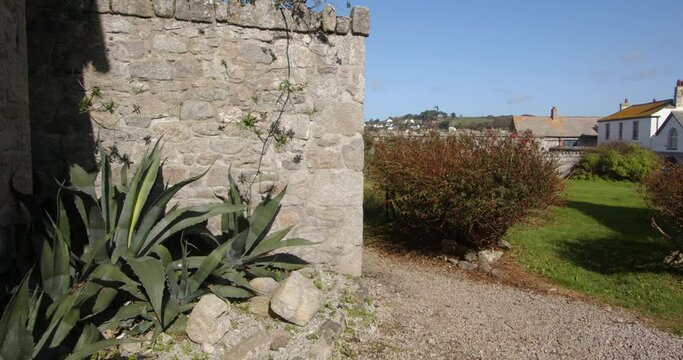 stone outbuilding with a fuchsia Bush and Agave America