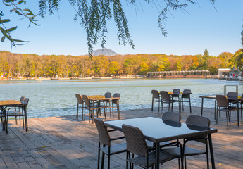 Recreation area in the city park. Outdoor tables and benches by the lake for relaxing and eating