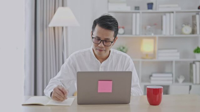 Smart Asian man smiling wearing glasses working with computer laptop. concept work form home, stay at home. freelance life style, New normal social distancing lifestyle. Work form anywhere concept.