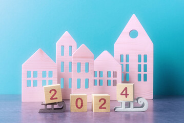 Wooden cubes with number 2024 over decorative wooden houses. New Year and Christmas greeting concept - 684477419