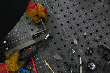 a worker assembles a metal structure on a table, top view